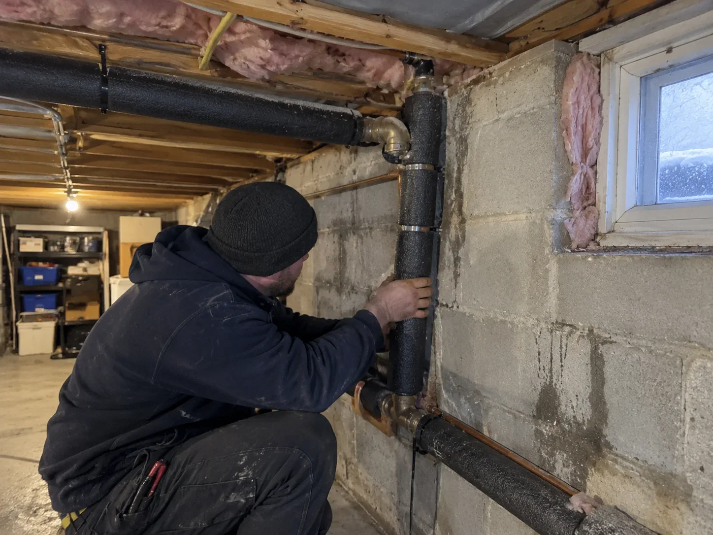 Plumber repairing a frozen supply pipe on an exterior wall in a St. Catharines home